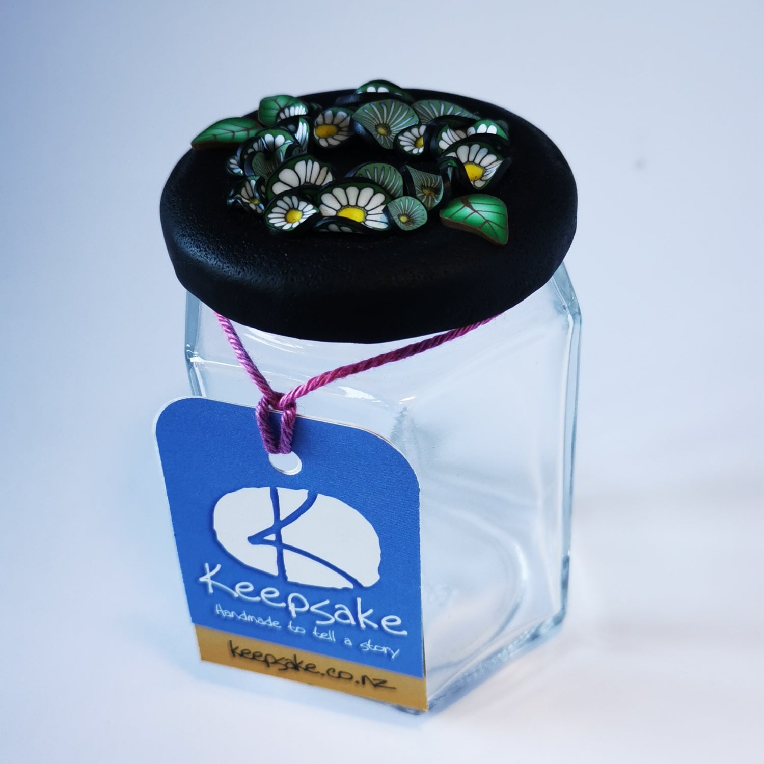 185ml glass hexagonal  jar and lid hand-decorated in New Zealand, with  an air-tight lid decorated with polymer clay daisies in a daisy chain. Ready to be filled with fudge, sweets or other treasures.