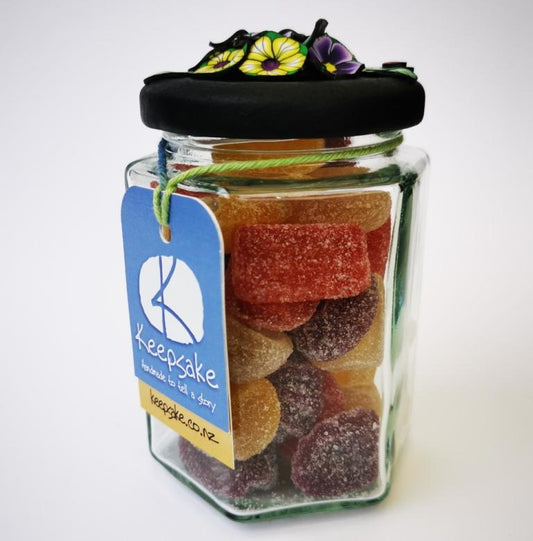 270ml glass hexagonal lolly jar hand-decorated in New Zealand, with  an air-tight lid decorated with colourful polymer clay flowers. Filled with flower jube sweets.