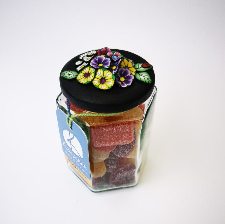 270ml glass hexagonal lolly jar hand-decorated in New Zealand, with  an air-tight lid decorated with colourful polymer clay flowers. Filled with flower jube sweets.