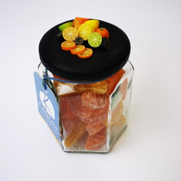 270ml glass hexagonal lolly jar hand-decorated in New Zealand, with  an air-tight lid decorated with miniture polymer clay  oranges, lemons, limes and passionfruit. Filled with orange and lemon jubes (jelly lollies)