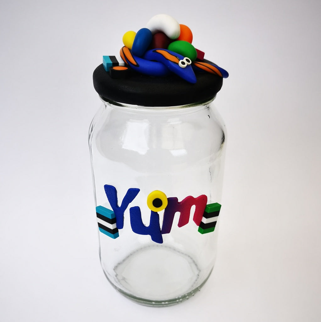 Extra-large glass treat jar hand-decorated in New Zealand, with an air-tight lid decorated with colourful polymer clay licorice allsorts, jelly beans and a blue snake, and with polymer clay YUM on the side. Perfect for the whole family or as a gift for Nana or Granddad.
