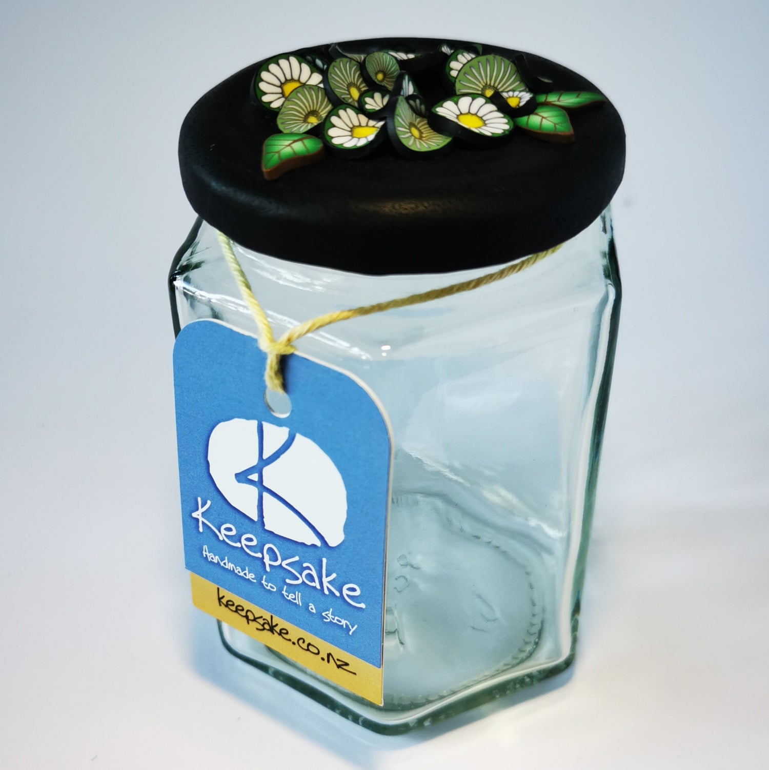 270ml glass hexagonal  jar and lid hand-decorated in New Zealand, with  an air-tight lid decorated with polymer clay daisies in a daisy chain. Ready to be filled with fudge, sweets or other treasures.