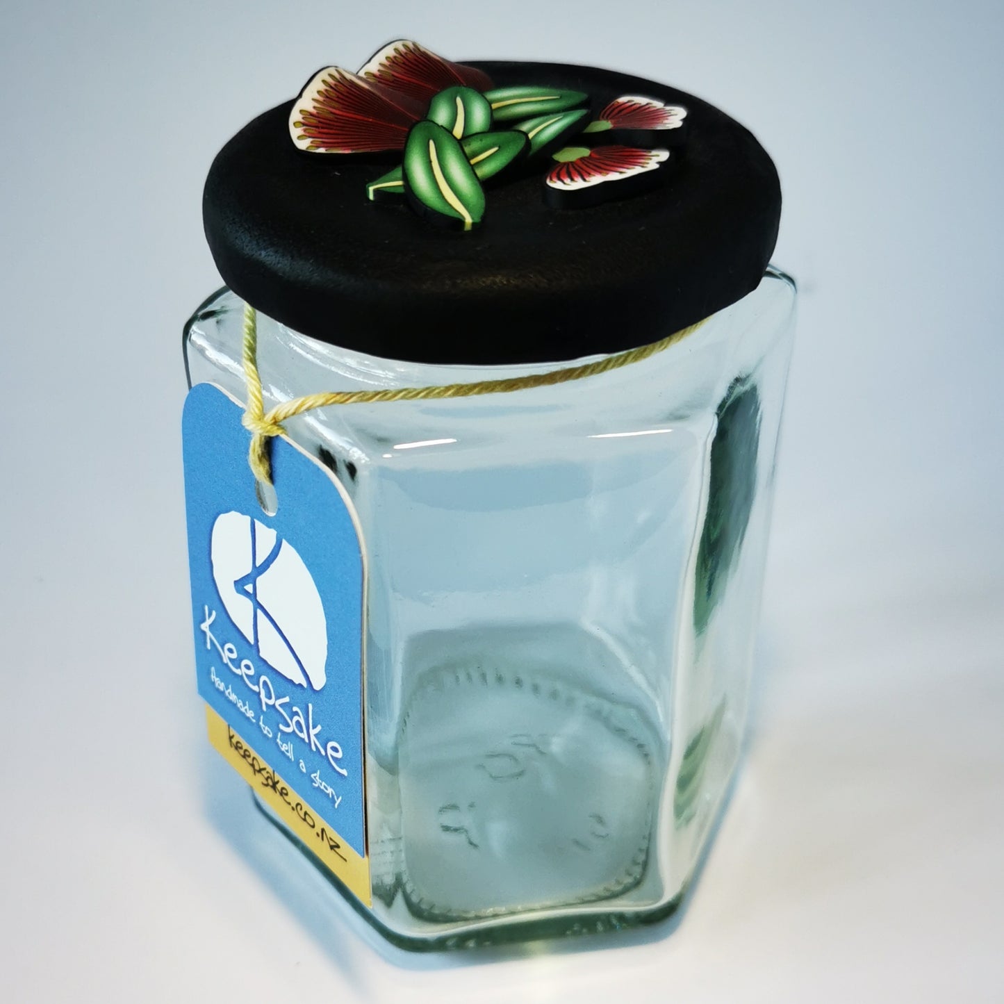 270ml glass hexagonal  jar and lid hand-decorated in New Zealand, with  an air-tight lid decorated with polymer clay pohutukawa flowers and leaves. Ready to be filled with fudge, sweets or other treasures.