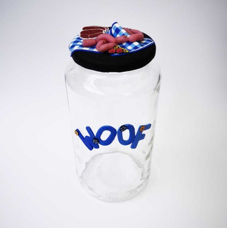 Round Dog glass treat Jar hand-decorated in New Zealand,  with  blue WOOF on the front and a polymer clay decorated air-tight lid, including a blue tablecloth, miniture sausages and steak as a gift for that special dog